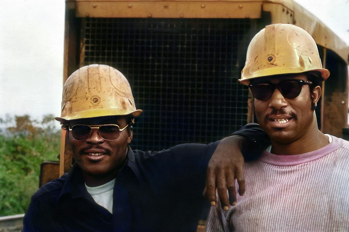 Deux ouvriers souriants portant un casque de chantier