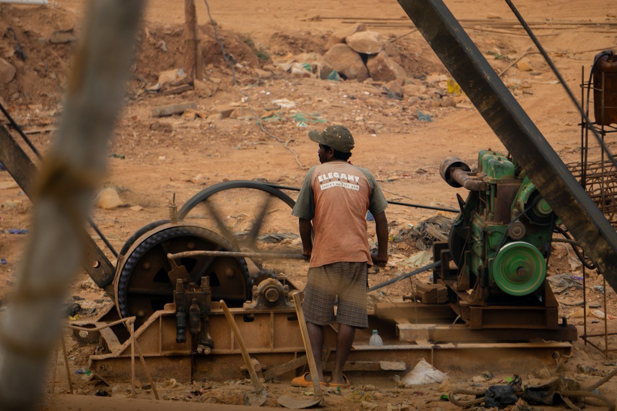 Exploitant près de ses machines sur un site minier artisanal en terre rouge